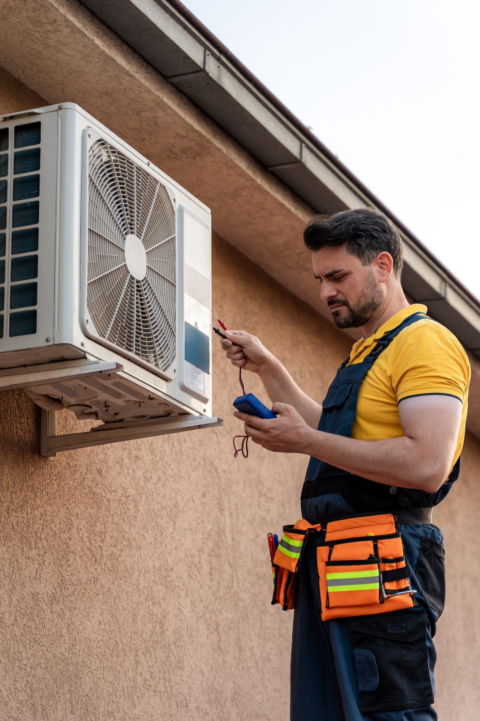 An HVAC technician testing an air conditioning unit with a multimeter