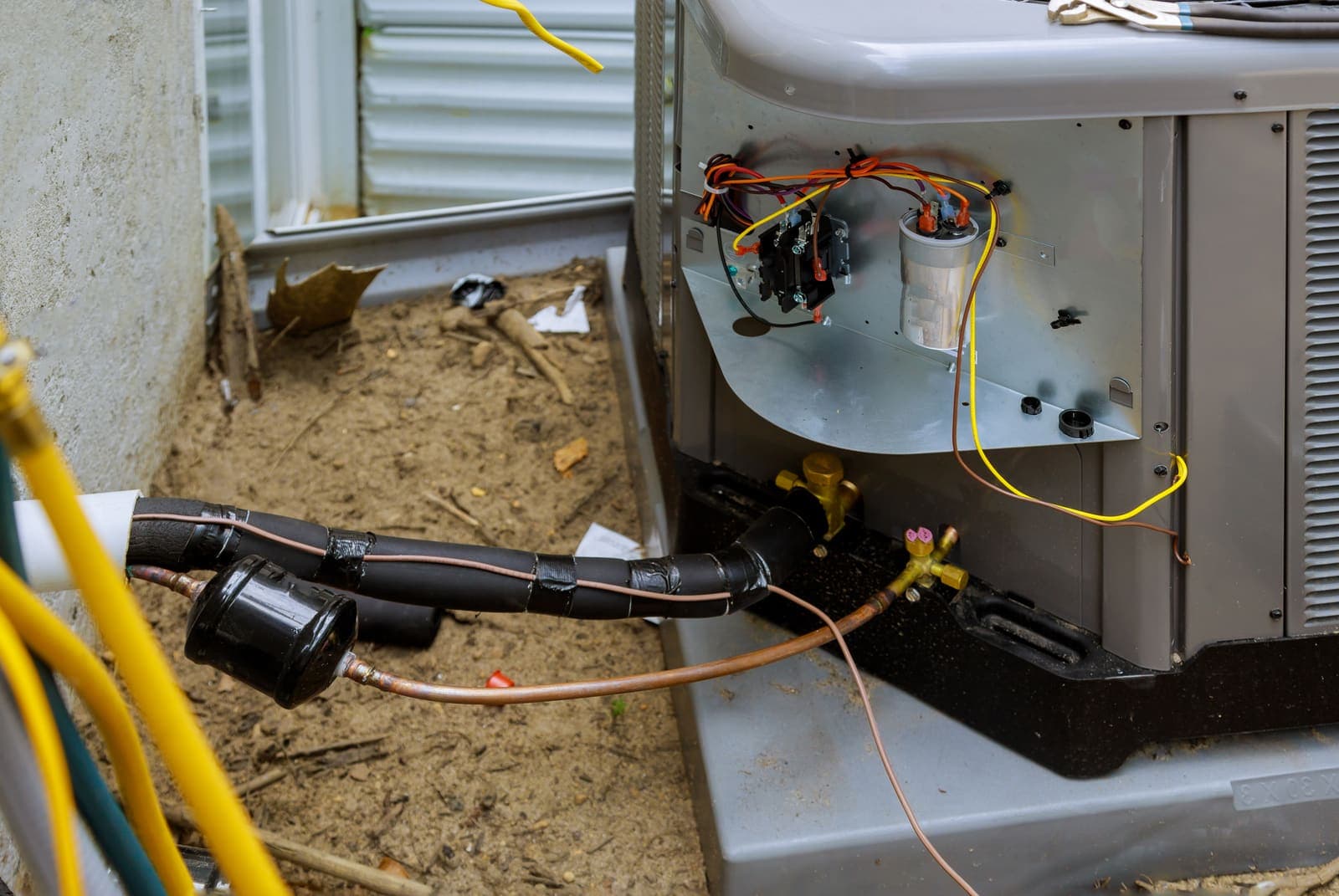 The inside of an air conditioner unit showing copper refrigerant lines and wiring