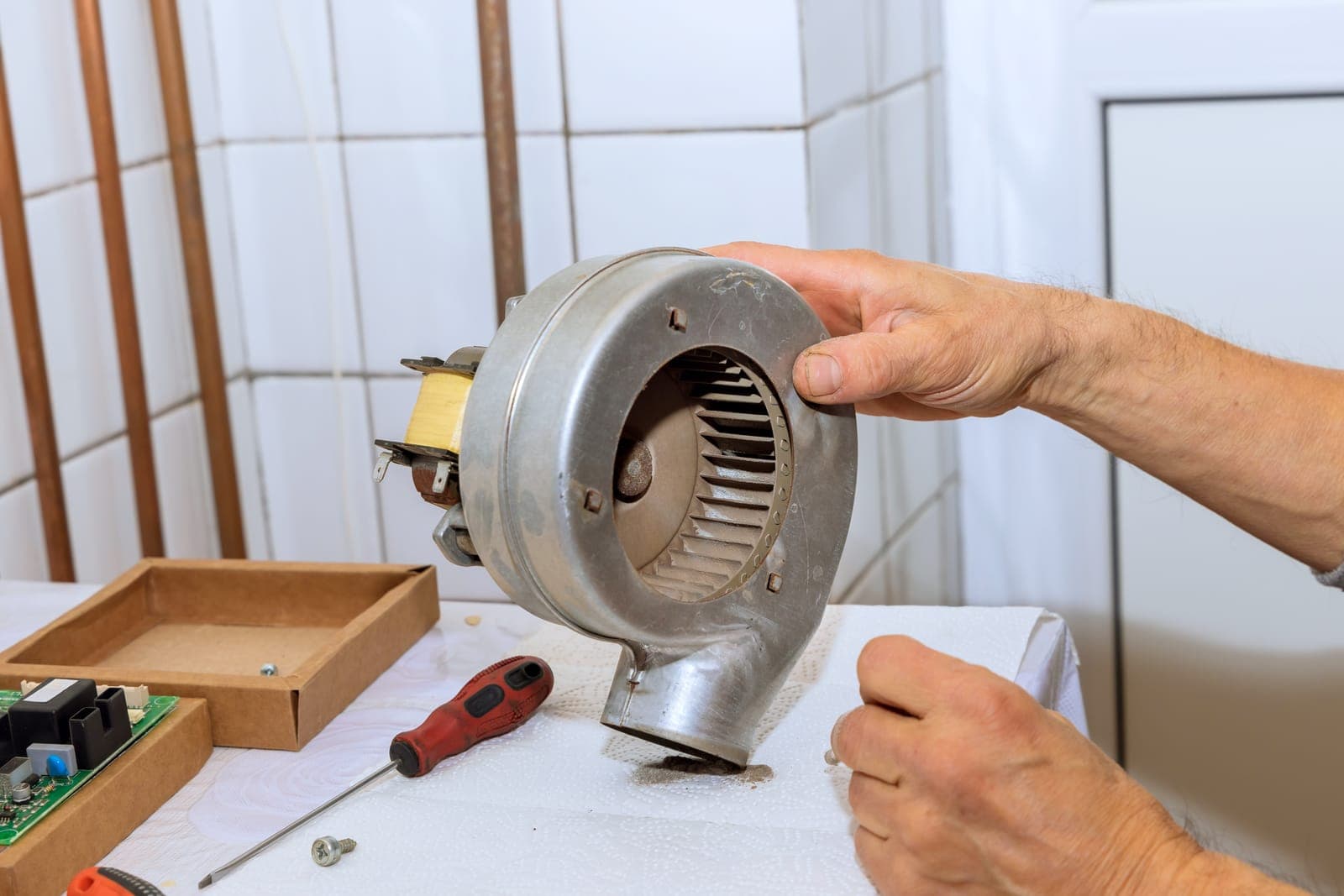 A technician servicing an HVAC blower assembly