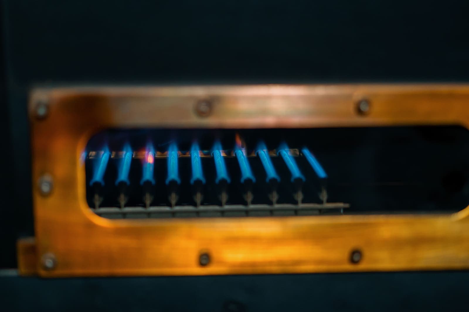 Bright blue gas flames igniting inside a metal burner frame
