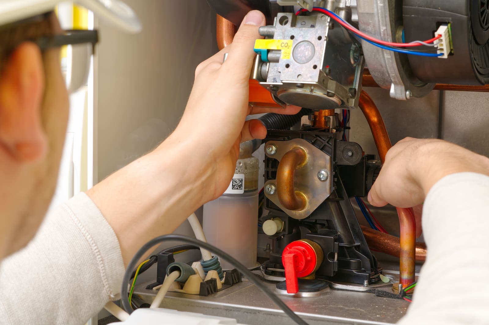 A technician working on the motor and components inside a furnace cabinet