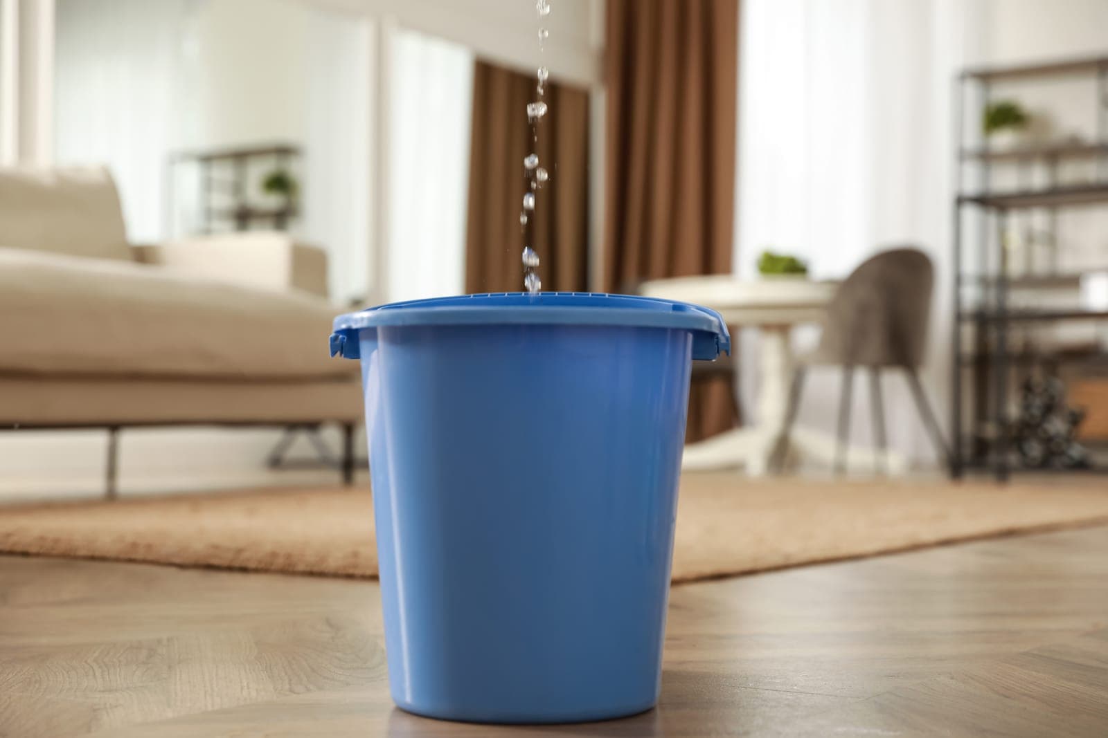 Water dripping into a bucket from a leak inside a home