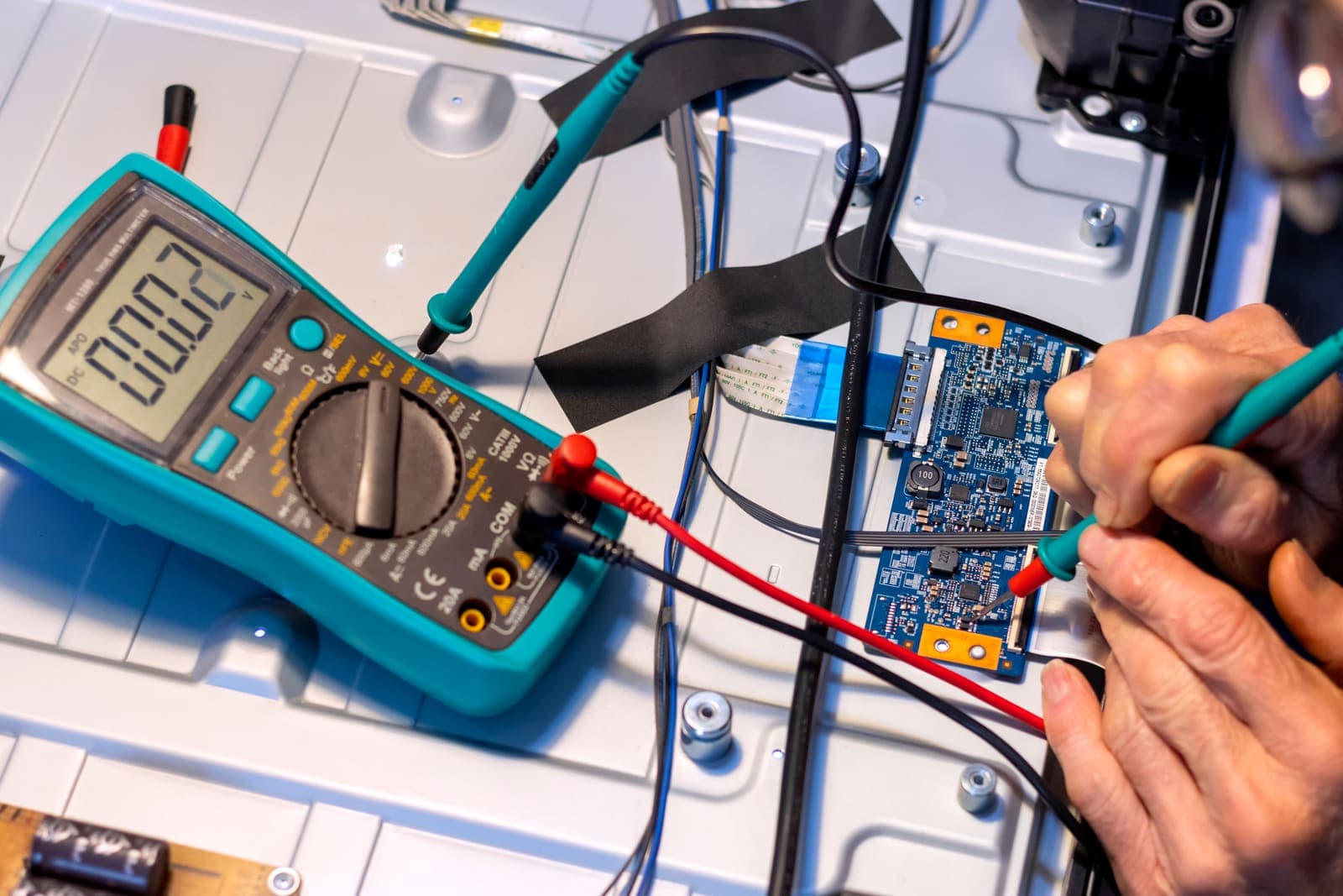 A technician testing an electronic circuit board with a multimeter