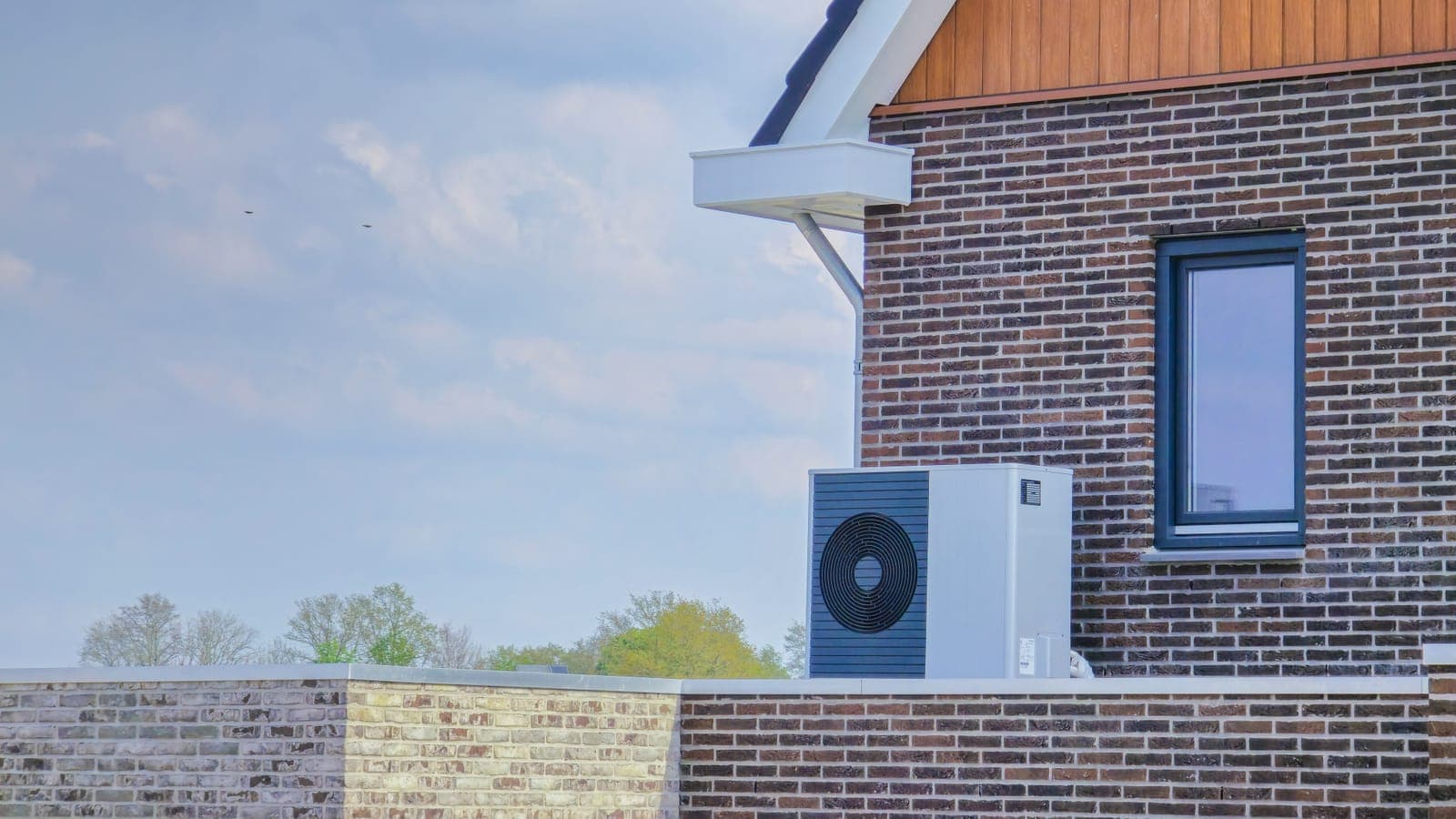 An air source heat pump installed outside a modern brick home