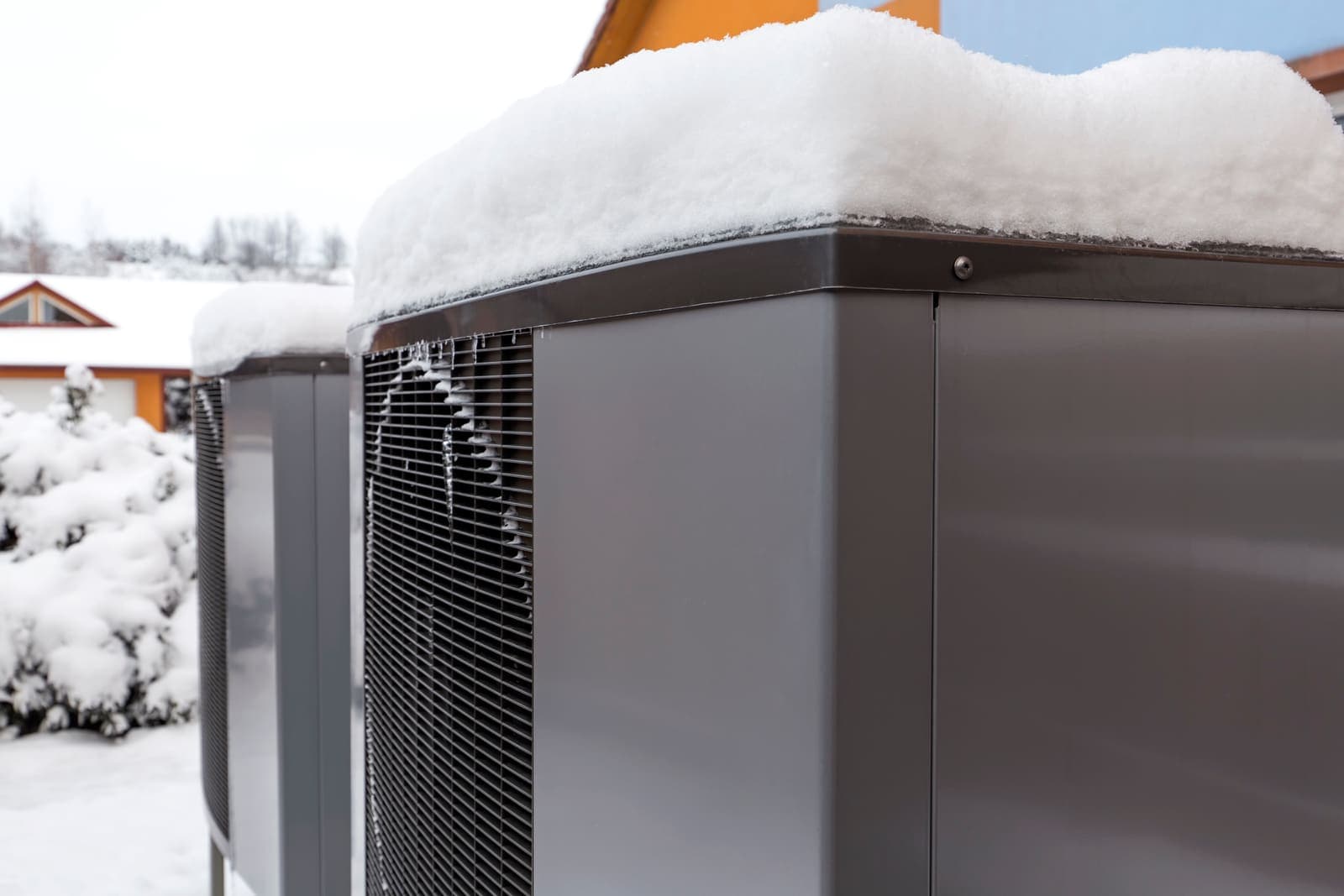 A heat pump outdoor unit covered in frost on a cold winter morning