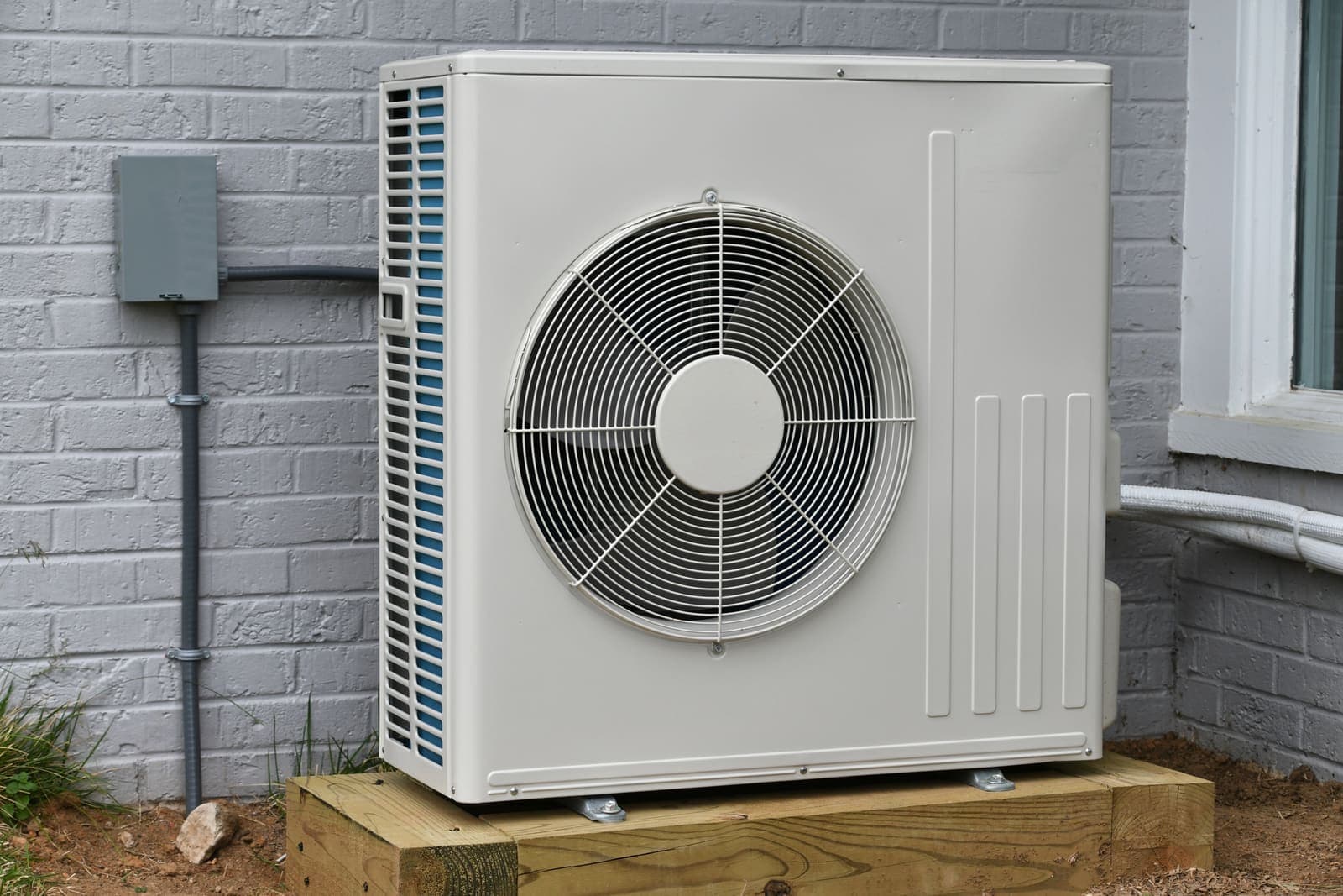 A modern white heat pump outdoor unit beside a home