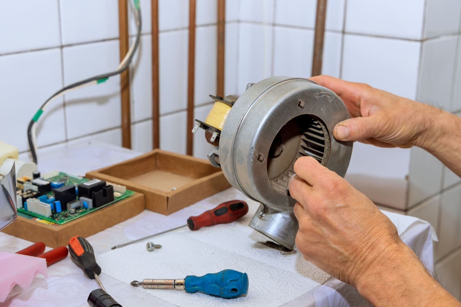 A technician repairing a blower fan motor on a workbench