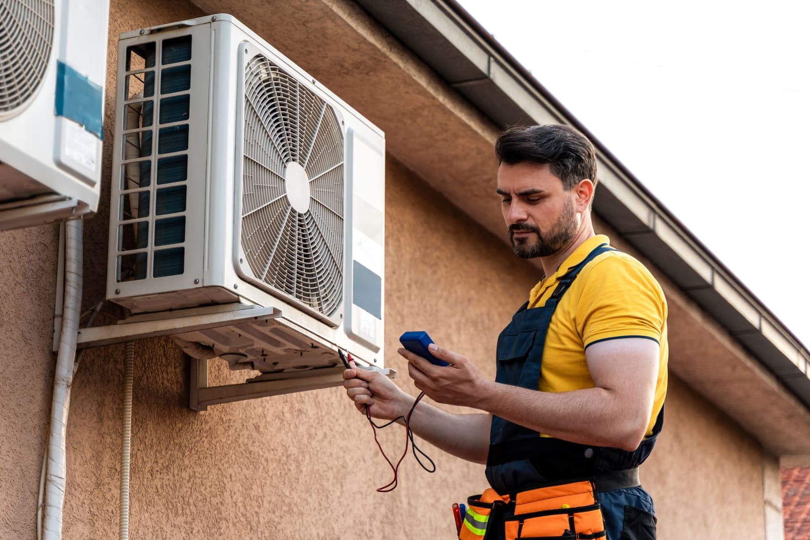 An HVAC technician using a meter to troubleshoot an air conditioning unit