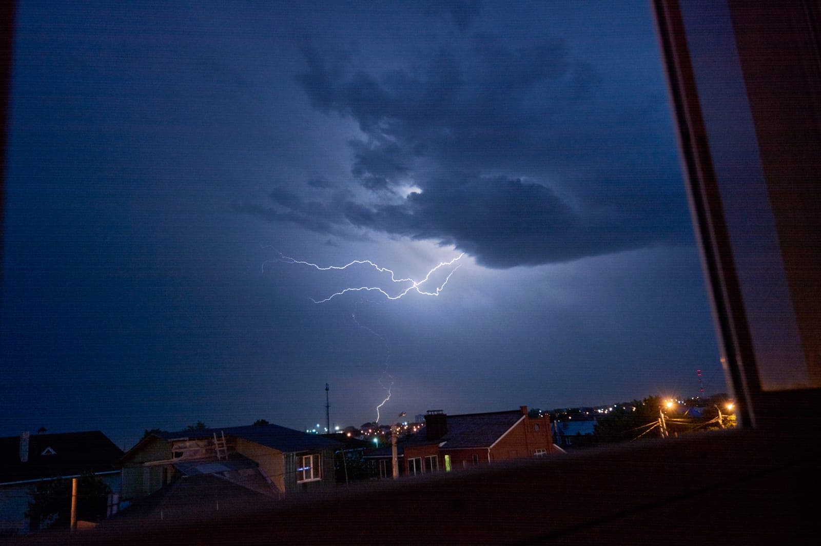 A dramatic lightning storm over a residential neighborhood at night