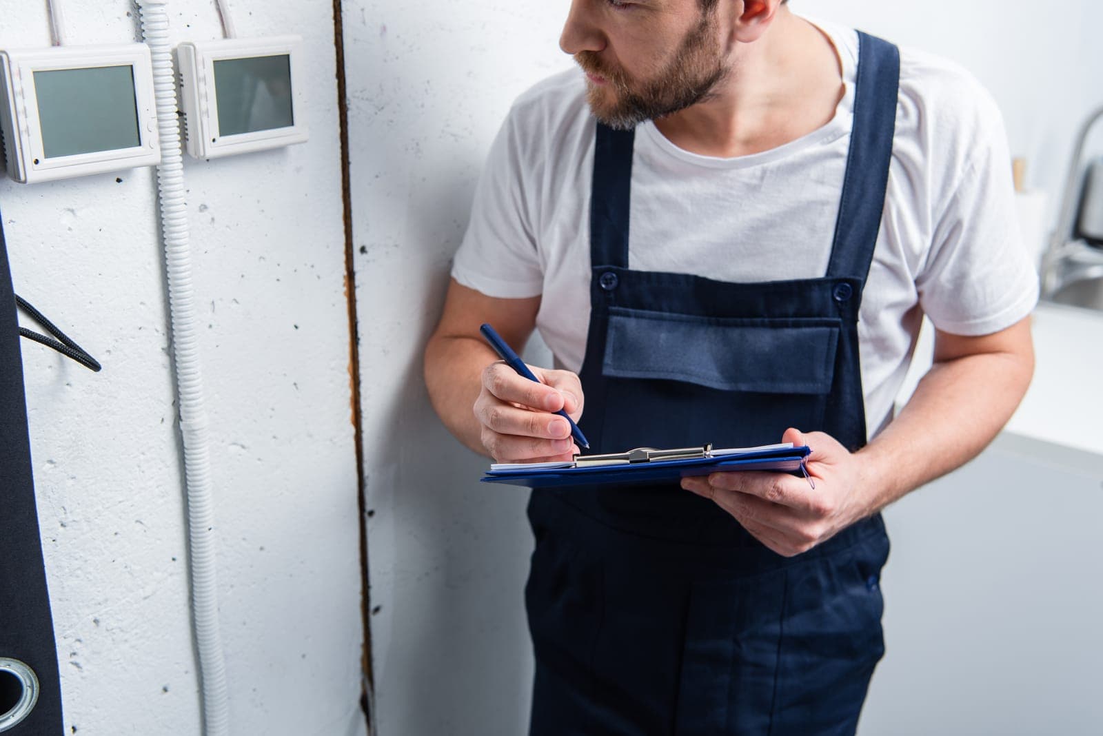 A maintenance technician taking notes during an HVAC inspection