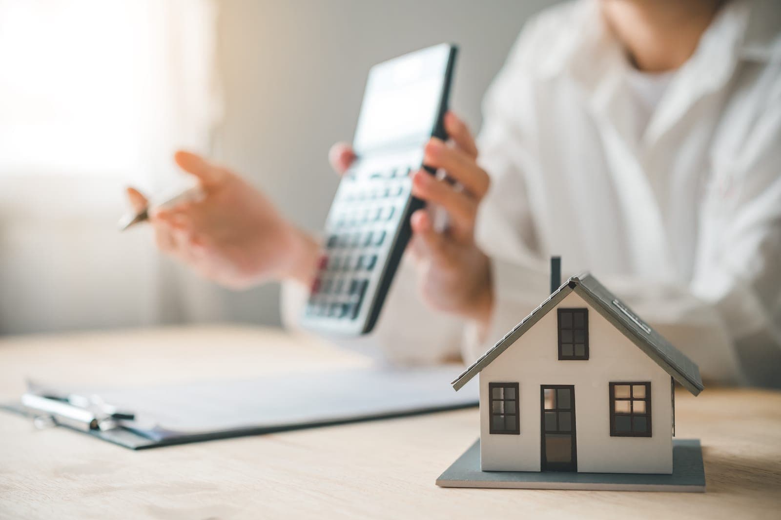 A homeowner budgeting for a new HVAC system with a calculator and model house