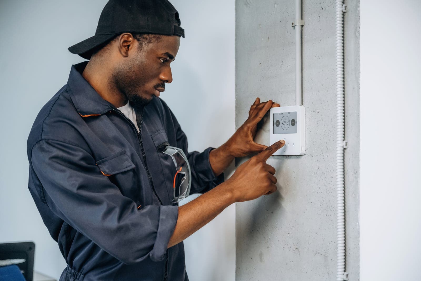 A technician installing a thermostat on a wall