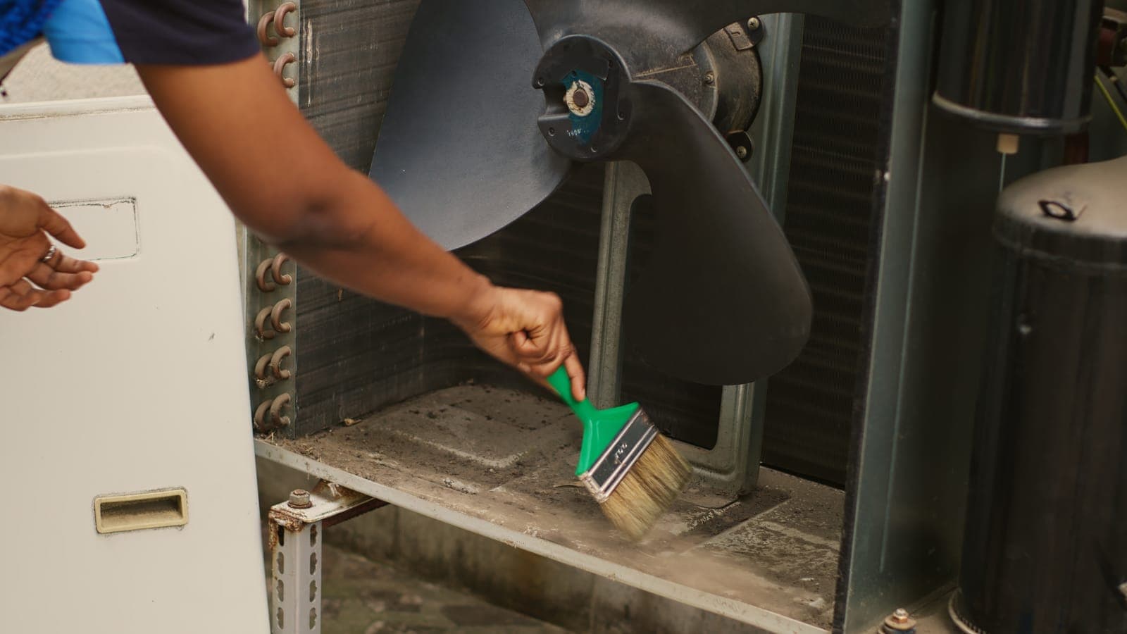 A technician cleaning an air conditioning unit during a tune-up
