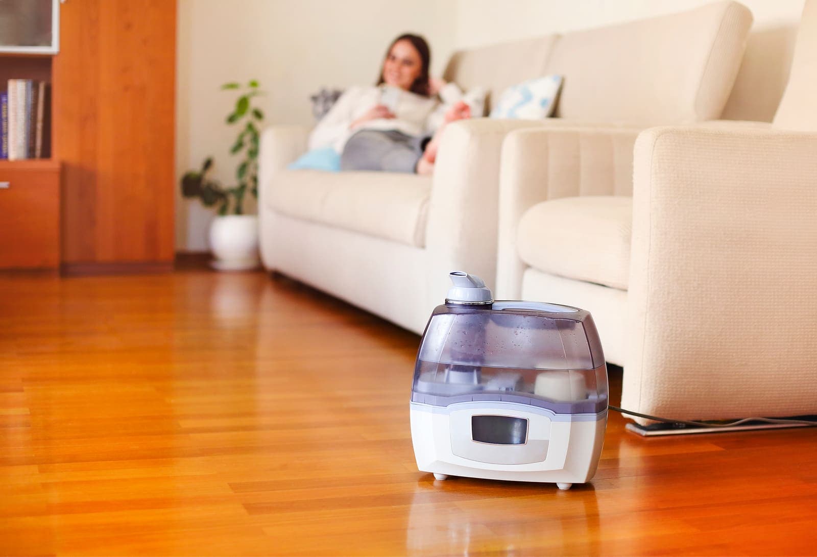 A humidifier running on a wood floor in a bright, comfortable living room