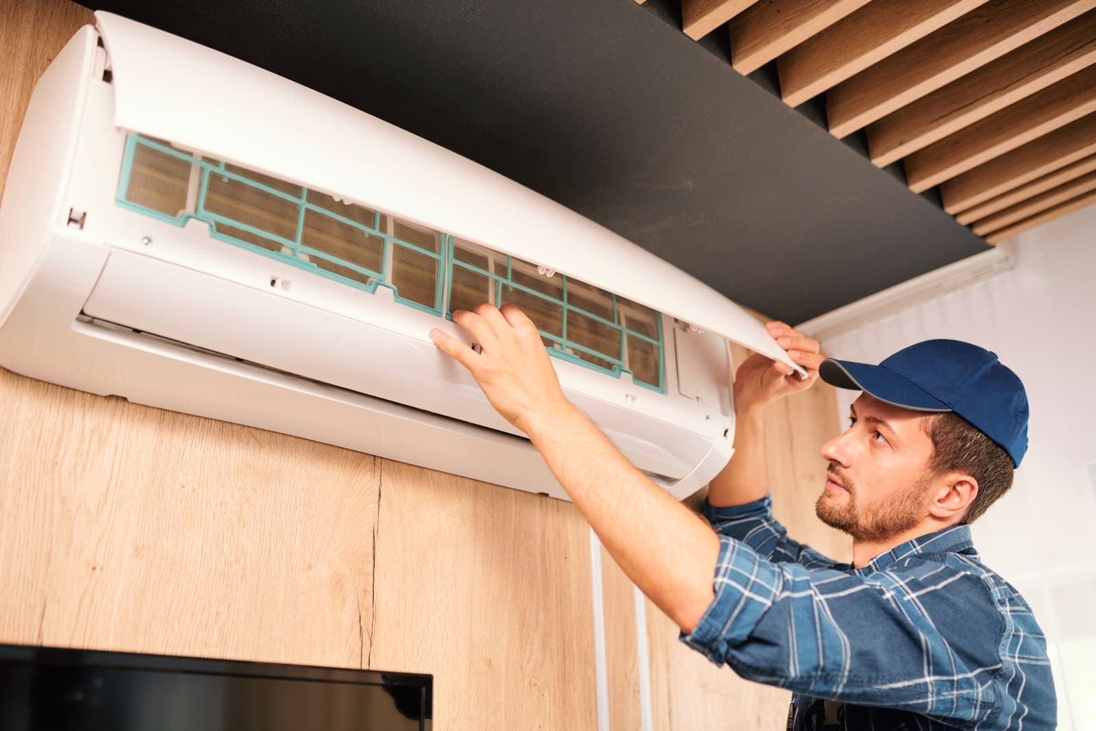 A technician installing a wall-mounted air conditioner in a home